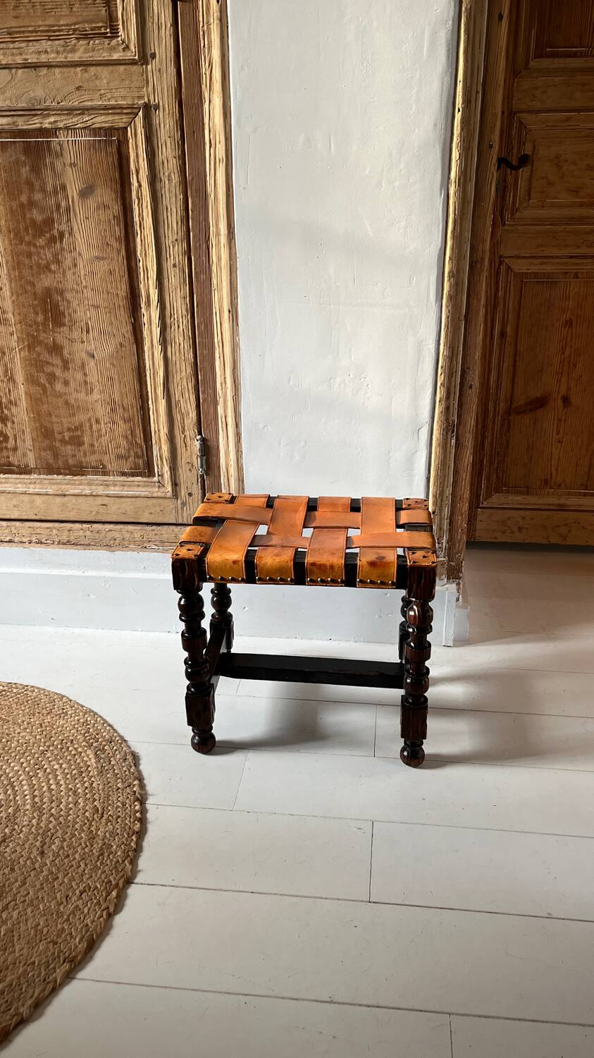 Antique turned wooden stool with woven leather.