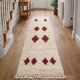Minimalist cream Berber rug with red diamonds.