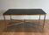 Neoclassical brass coffee table with a black leather top and golden borders from Maison Jansen.