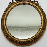 Antique oval gilded mirror with wooden frame and stucco detail