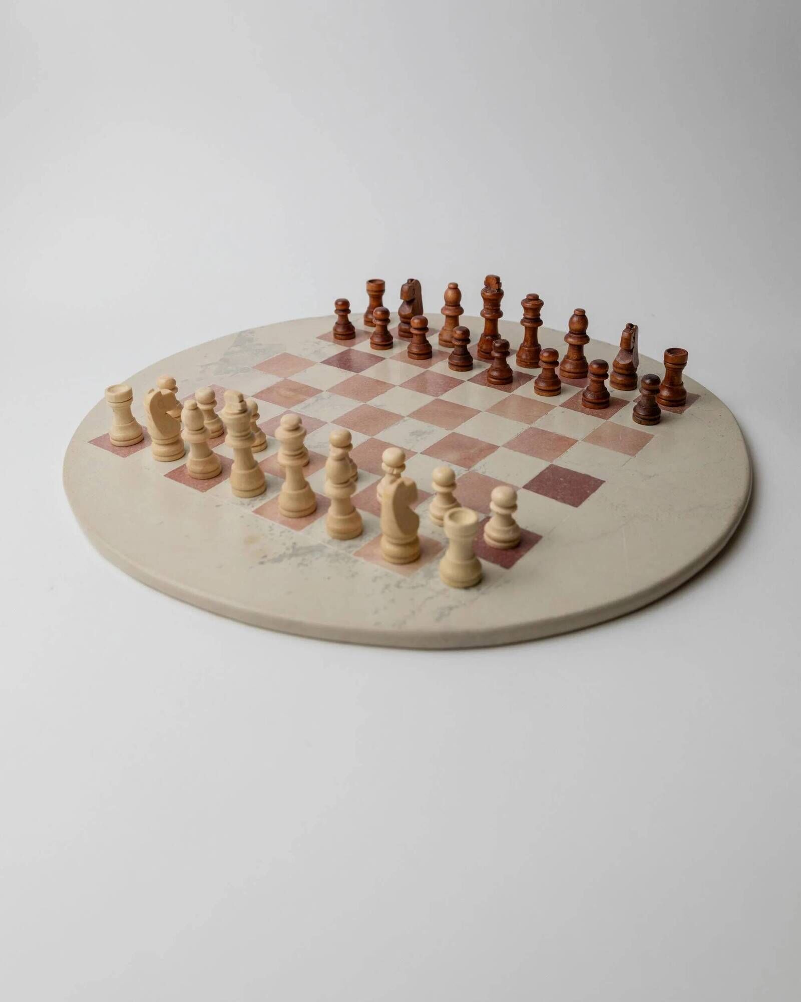 Vintage 1980s round chess set in marble, with a beige and pink marble board and wooden pieces.