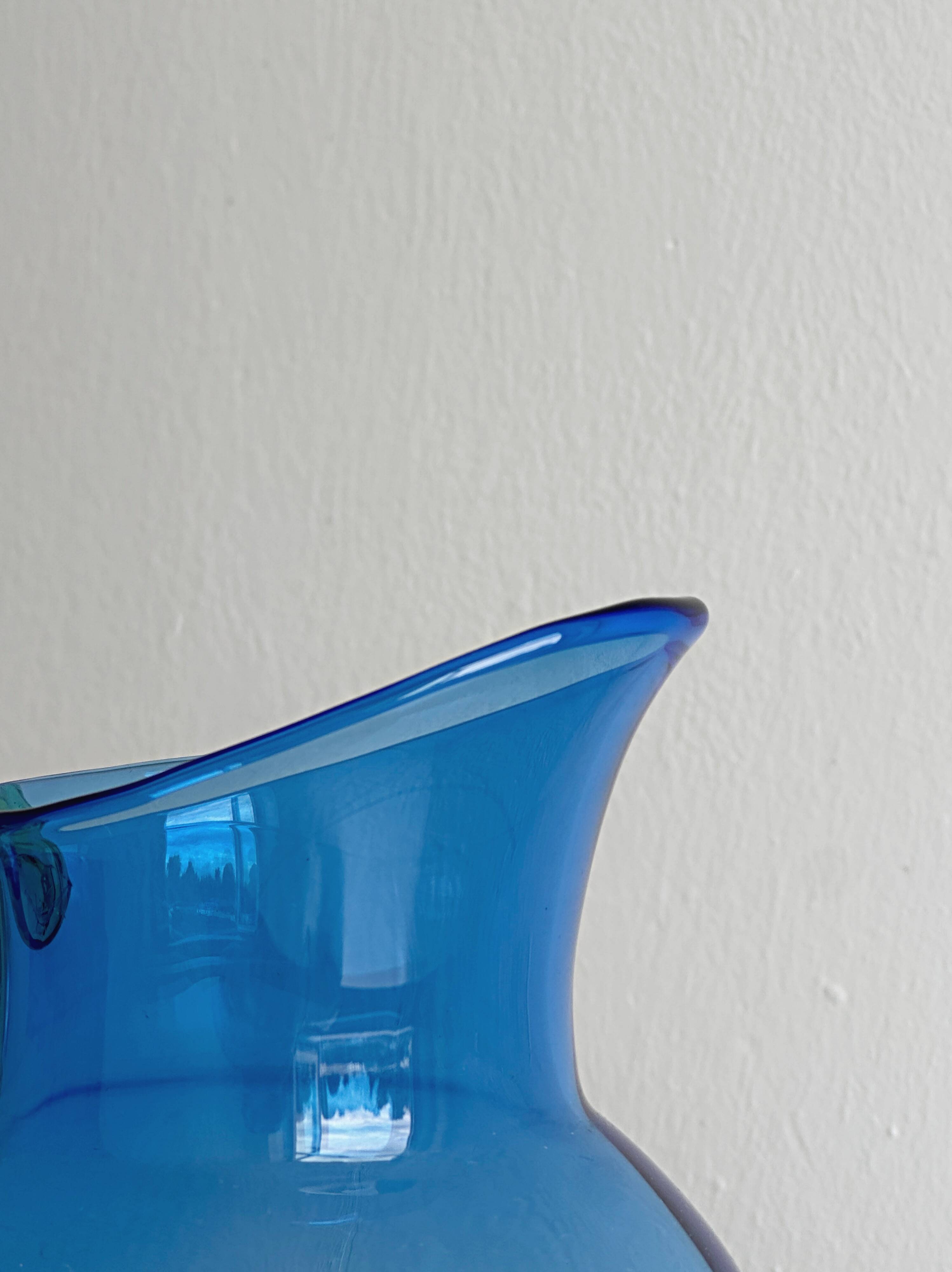 Translucent blue glass jug with a green handle.