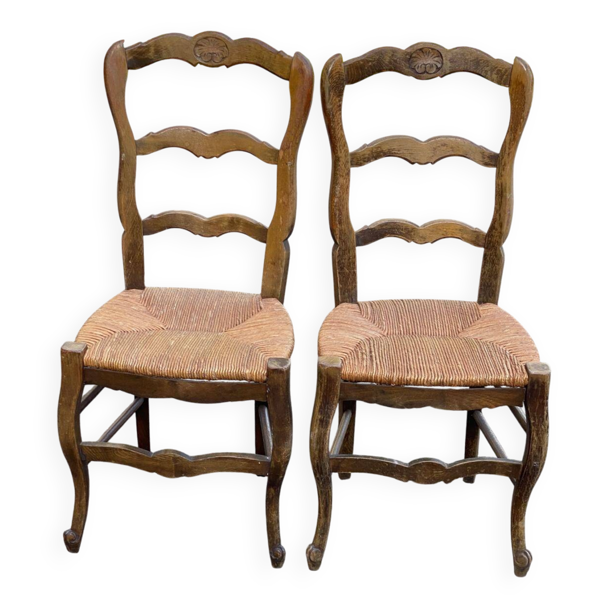 2 solid oak carved and rush-seated chairs in the Louis XV style from the 19th century.