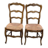 2 solid oak carved and rush-seated chairs in the Louis XV style from the 19th century.