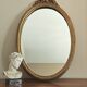 Vintage oval mirror with a carved wooden frame in gold, decorated with a bow.