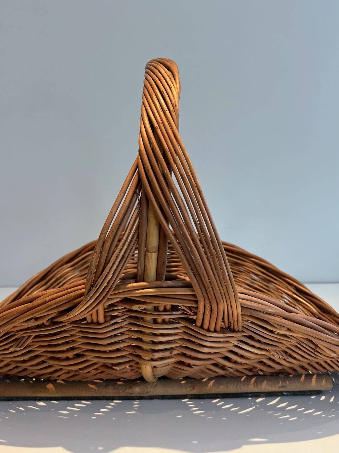 Woven Rattan Log Holder in a Semi-Round Shape with a Central Arched Handle.