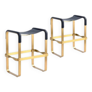 A pair of blue wanderlust stools without a backrest with brass.