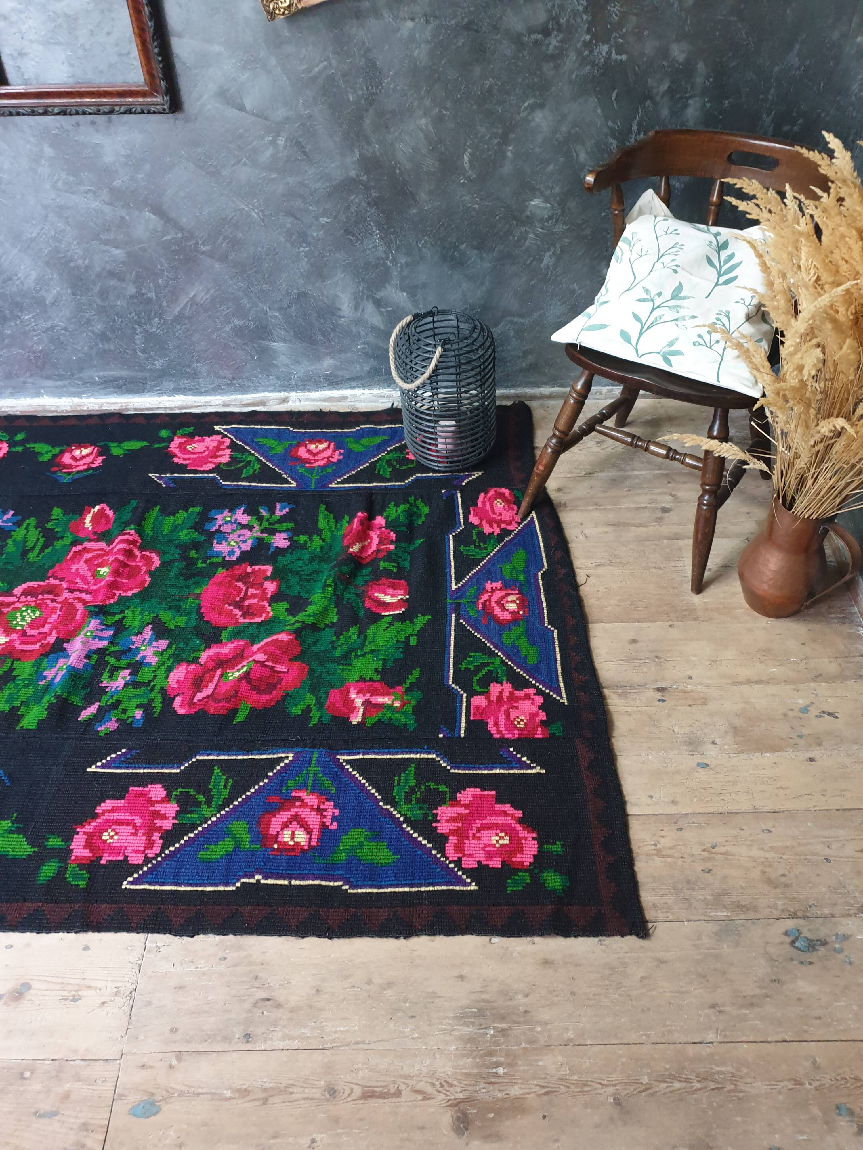 Handwoven floral wool rug, black background with pink roses