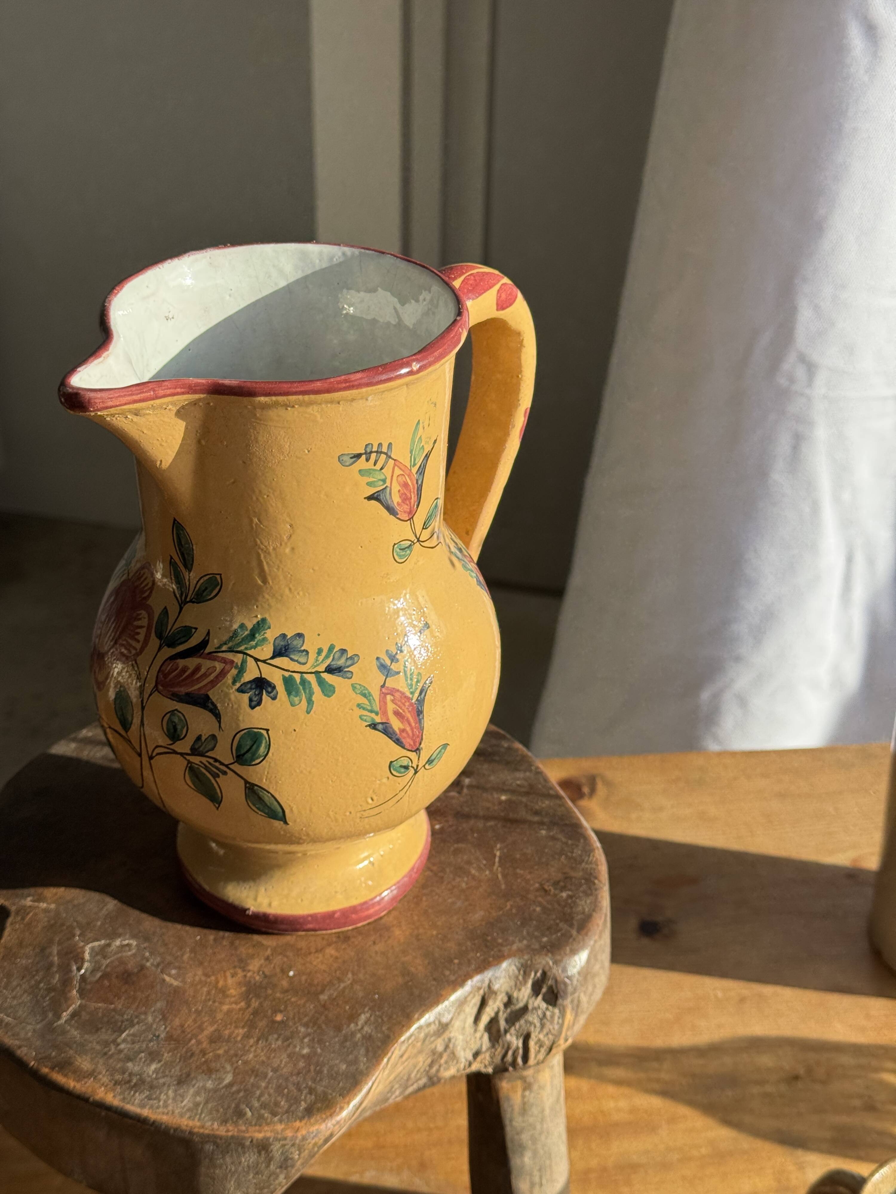 Large antique handmade ochre yellow jug with a pink flower pattern.
