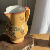 Large antique handmade ochre yellow jug with a pink flower pattern.