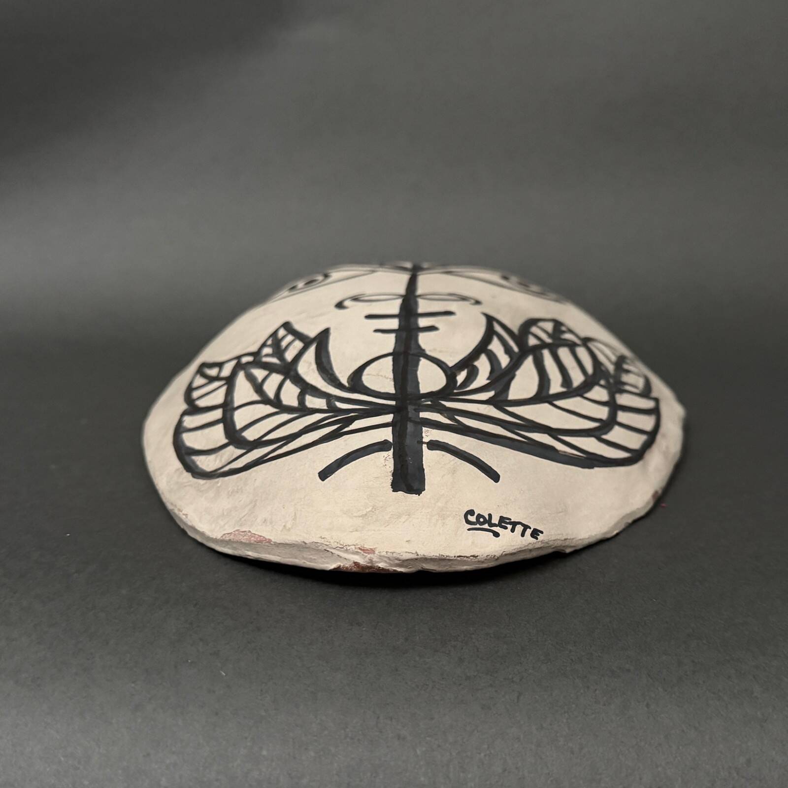 Africanist mask in glazed white terracotta, face signed Colette.