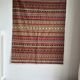 Large Indian rug with red, yellow, and white stripes and geometric fringes.