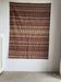 Large Indian rug with red, yellow, and white stripes and geometric fringes.