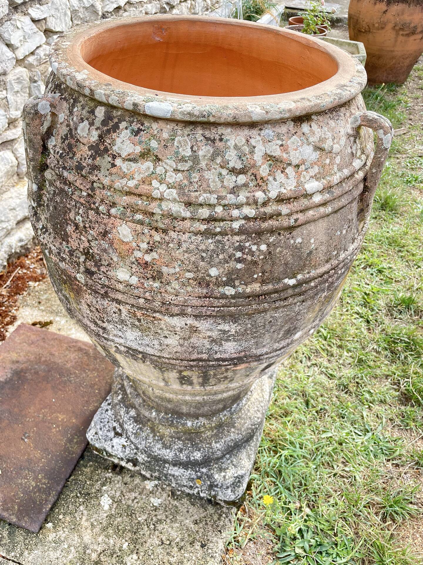 Large Cretan jar in terracotta with three handles on a stone base.
