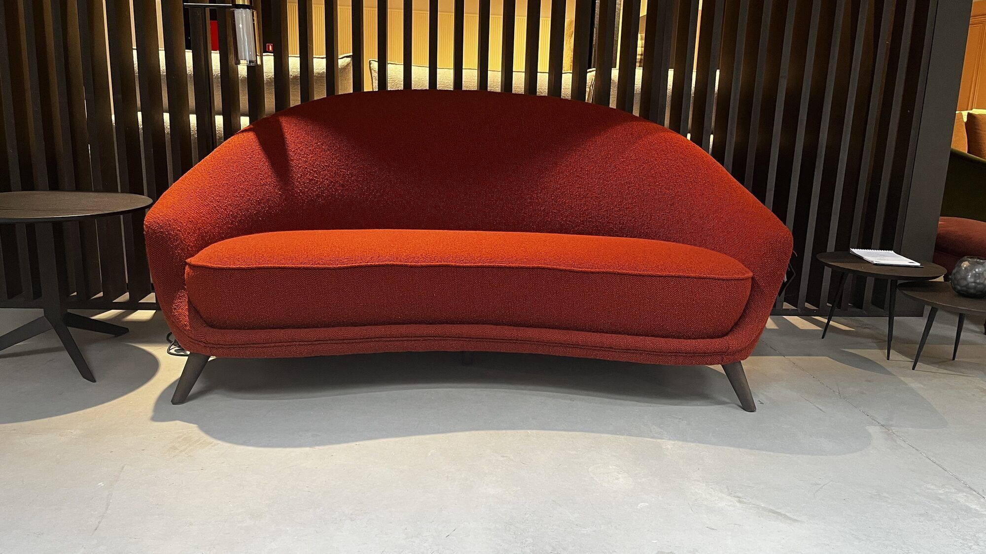 Two-seater sofa in red/orange boucle fabric.