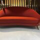 Two-seater sofa in red/orange boucle fabric.