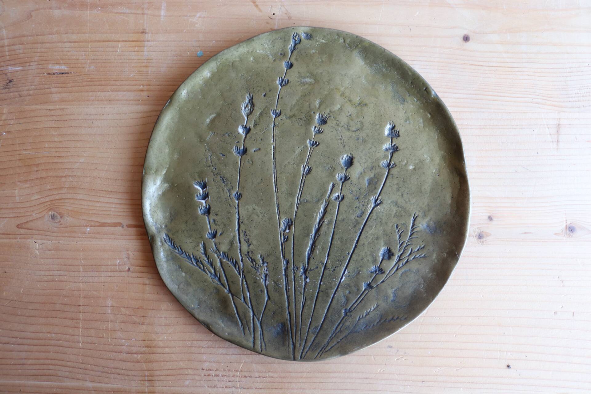 Decorative wall plaque in brass with a floral design.