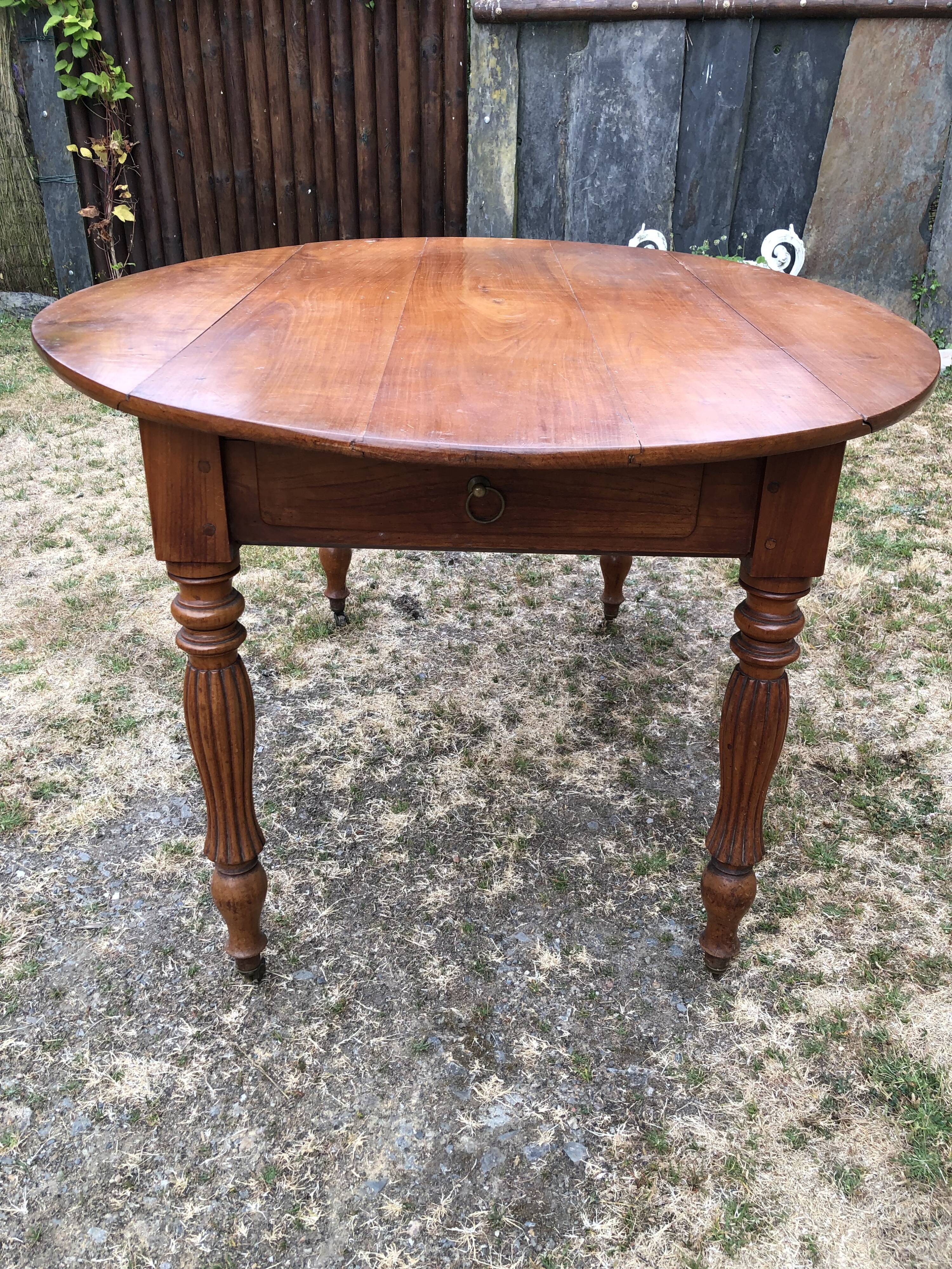 Louis Philippe oval drop-leaf table in solid cherry wood with 2 drawers.