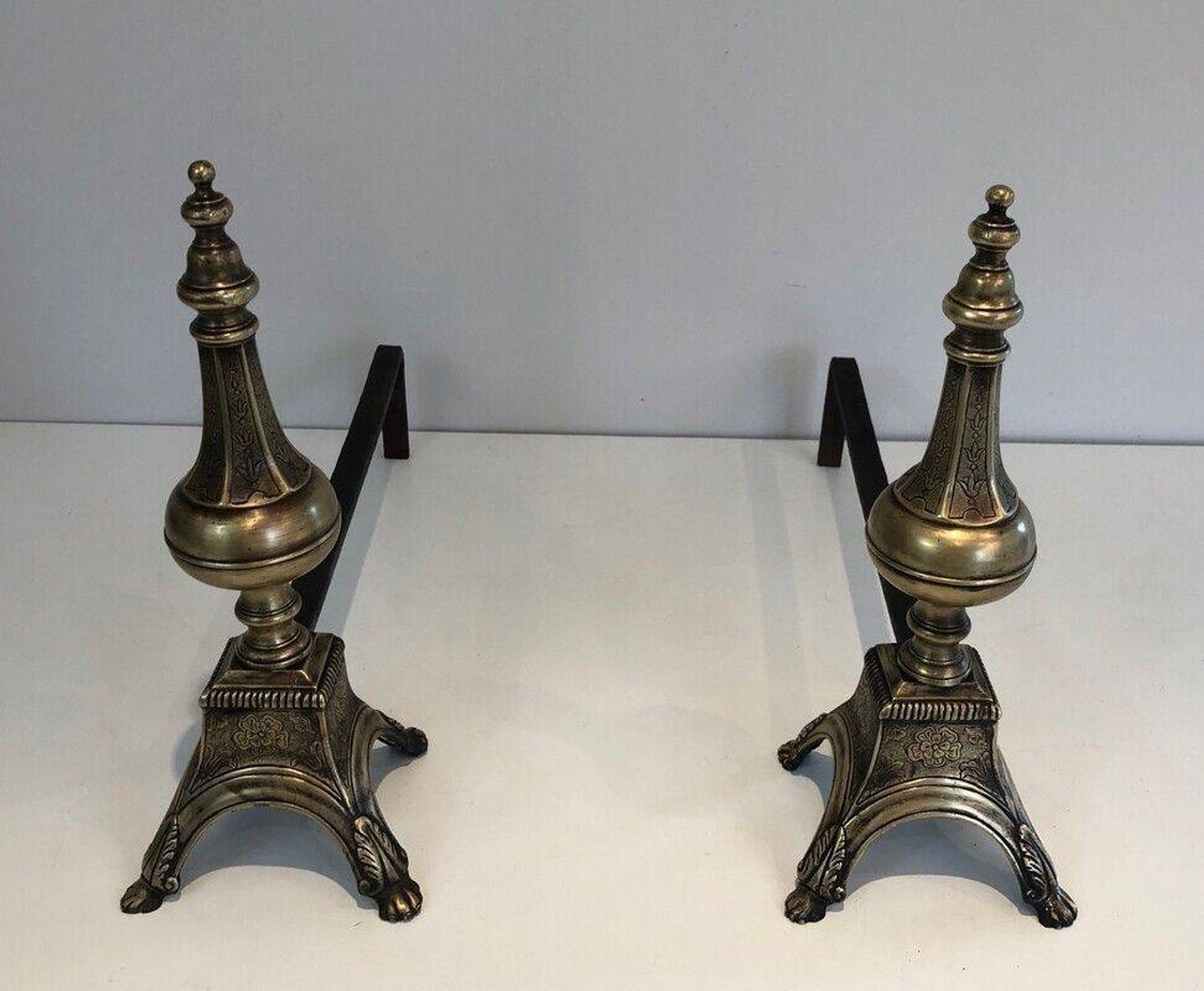 Pair of chiselled bronze and wrought iron fire dogs in the Louis XVI style.