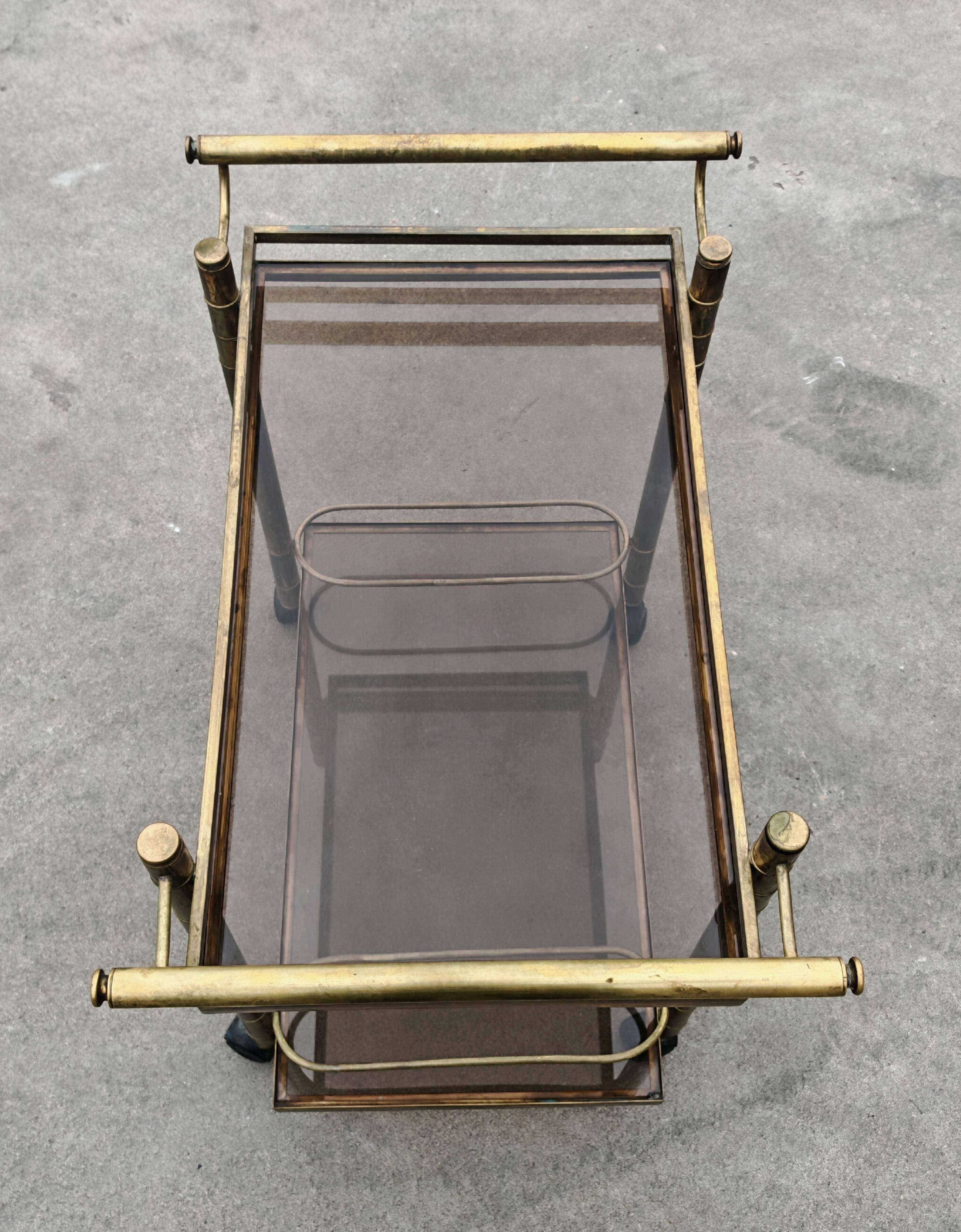 Mid Century Modern bar cart with 2 levels in brass and tinted glass.
