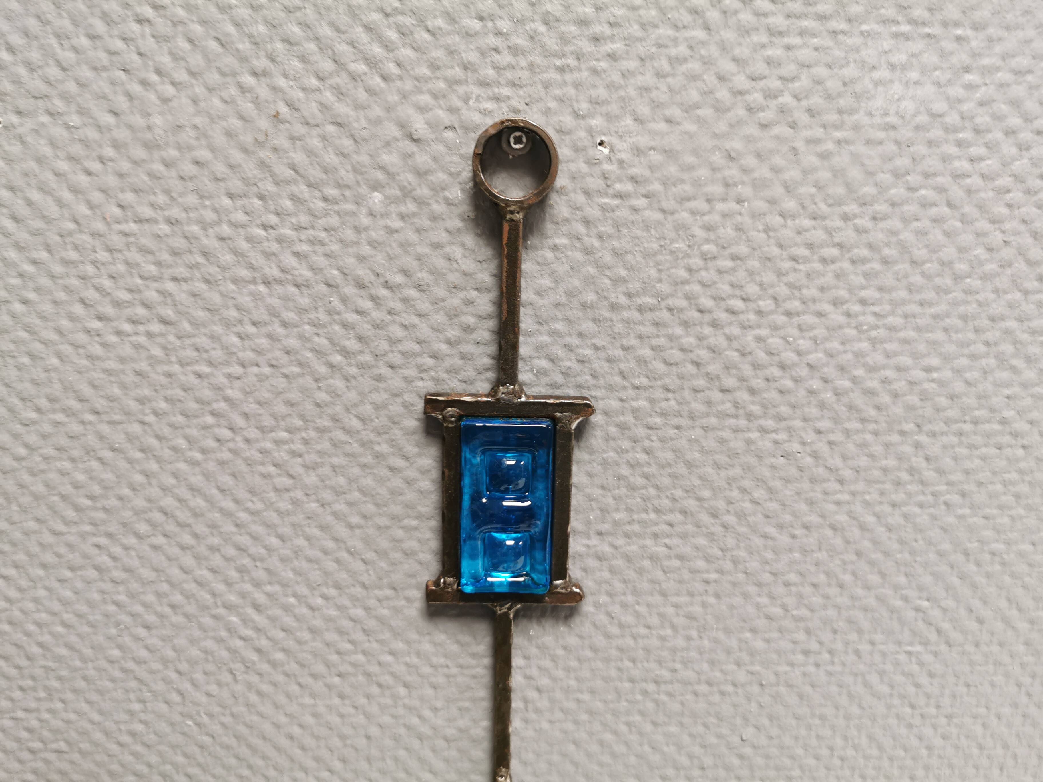 Wall-mounted candle holder in cast iron and hard pressed blue glass.