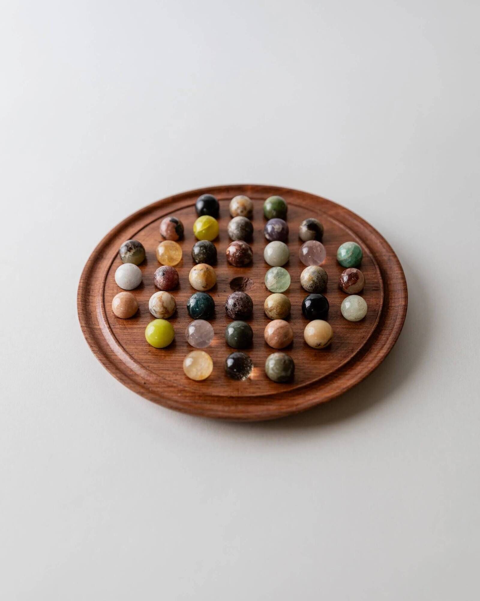Vintage 1960s solitaire game, wooden board with stone marbles.