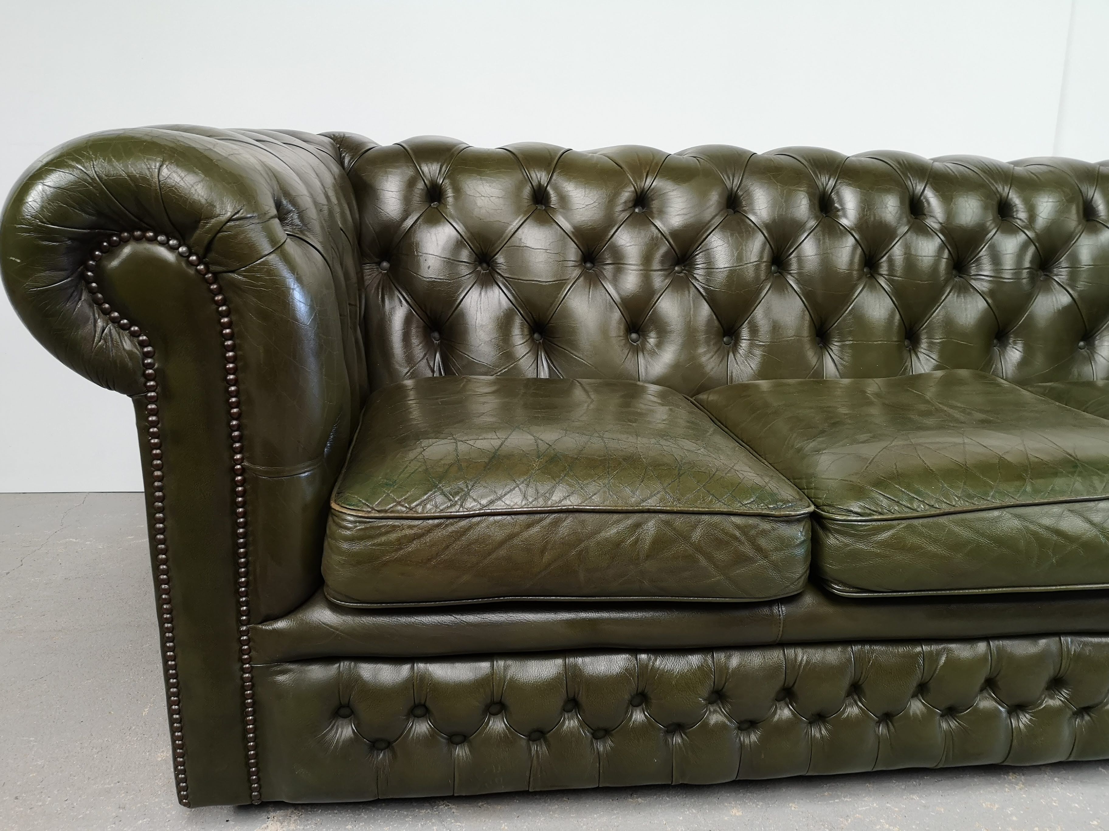 Three-seater green leather Chesterfield sofa