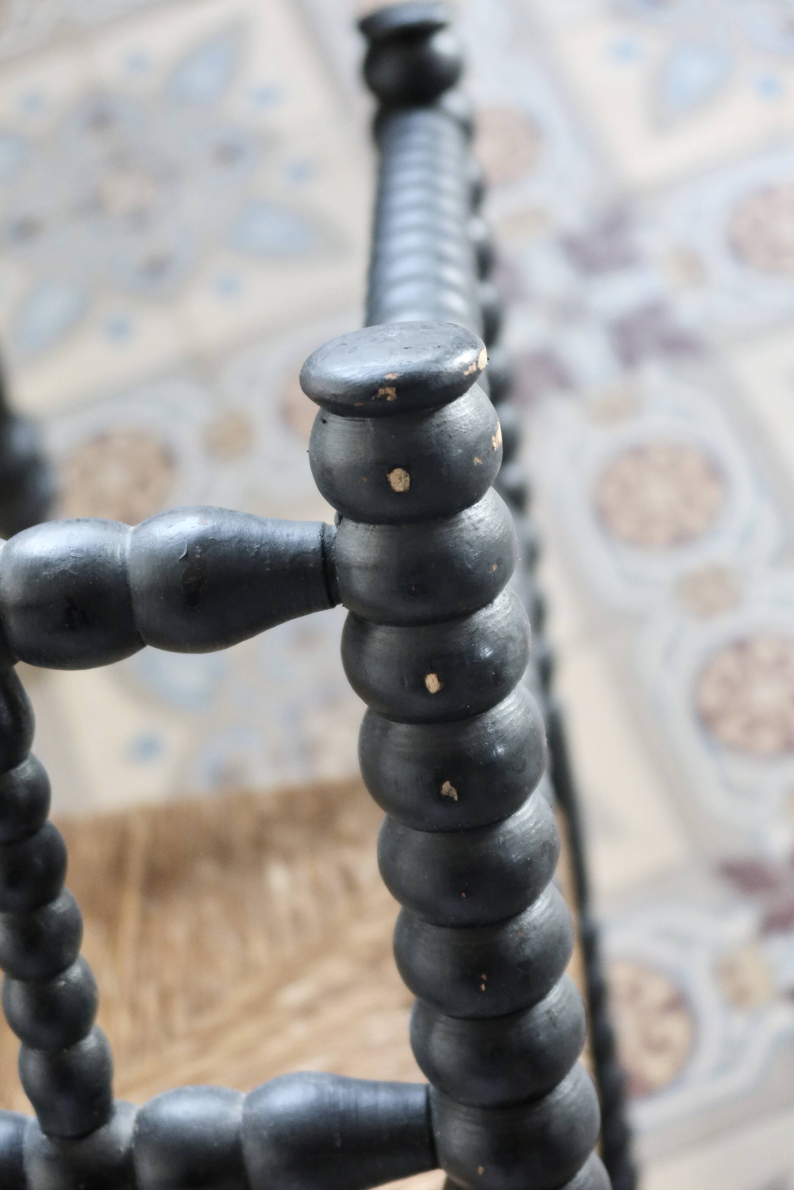 Antique black turned wood corner chair with a straw seat.