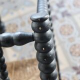 Antique black turned wood corner chair with a straw seat.