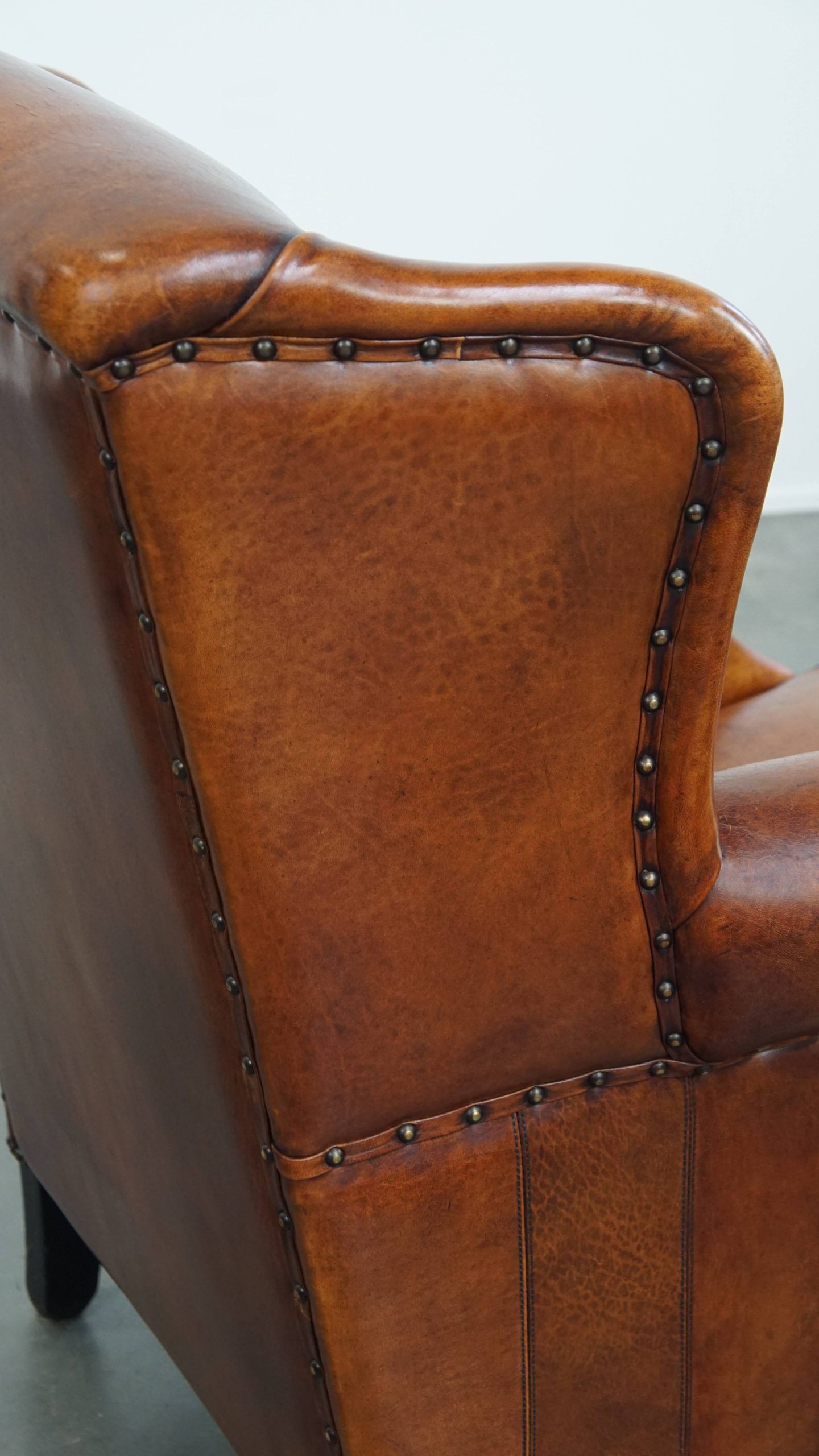 Sheepskin wingback armchair with stitching and black piping
