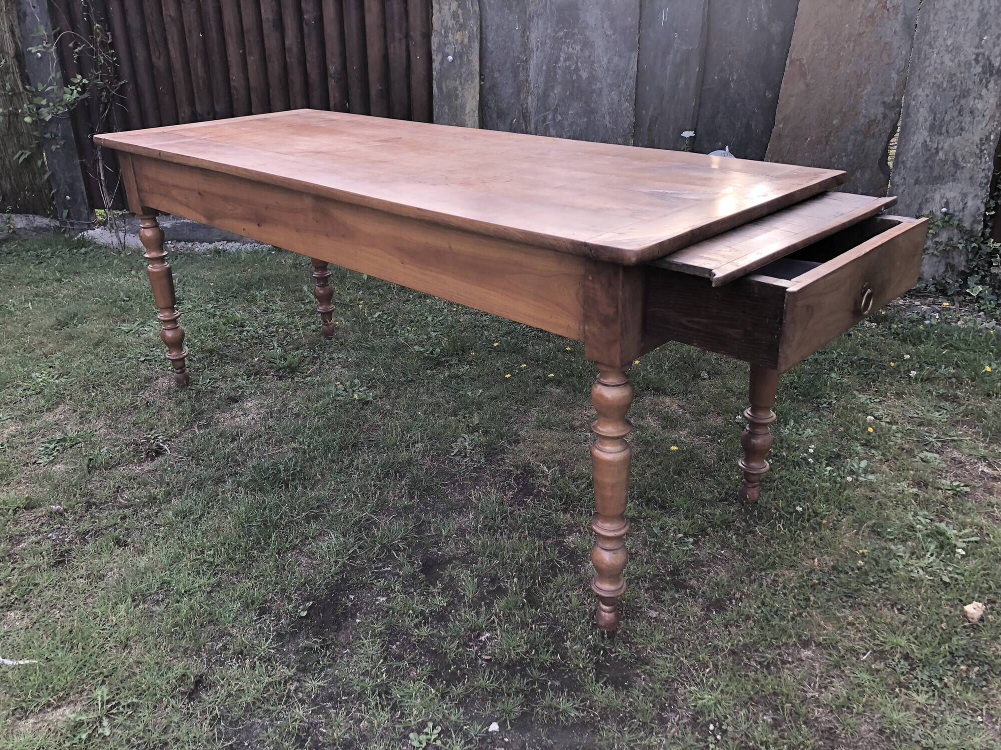 Antique farmhouse table in solid cherry wood with 2 drawers and 1 pull-out at the end with turned legs.