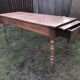 Antique farmhouse table in solid cherry wood with 2 drawers and 1 pull-out at the end with turned legs.