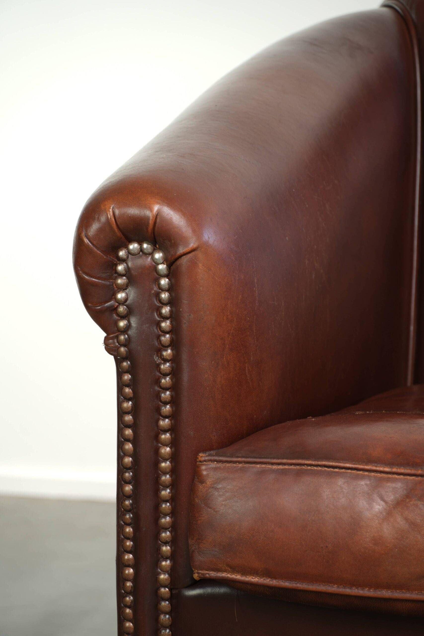 Characterful sheepskin club armchair in a dark cognac colour in English style