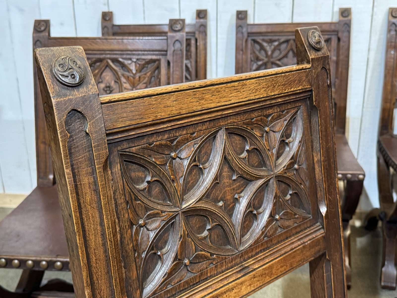 Suite de 6 chaises et 2 fauteuils en chêne et cuir à décor gothique