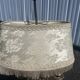 Two-armed hot water bottle lamp in silver metal with fringed fabric shade