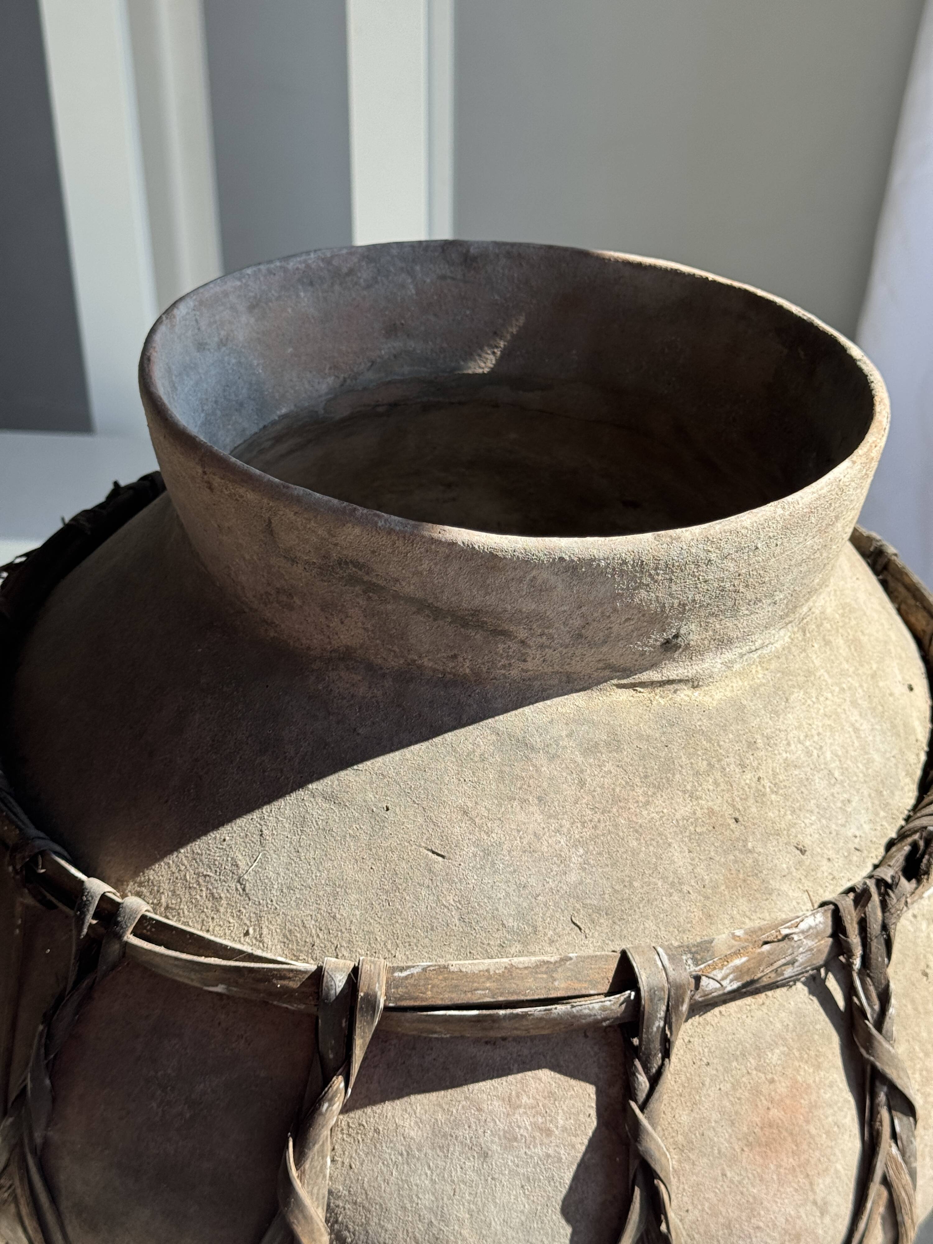 Very large light grey terracotta pot with handles and rattan crossbars.