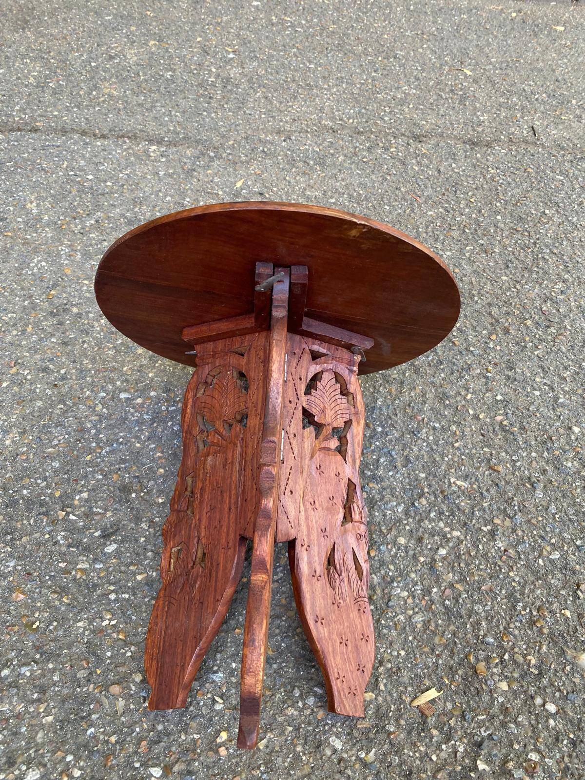 Round folding side table made of carved solid wood.
