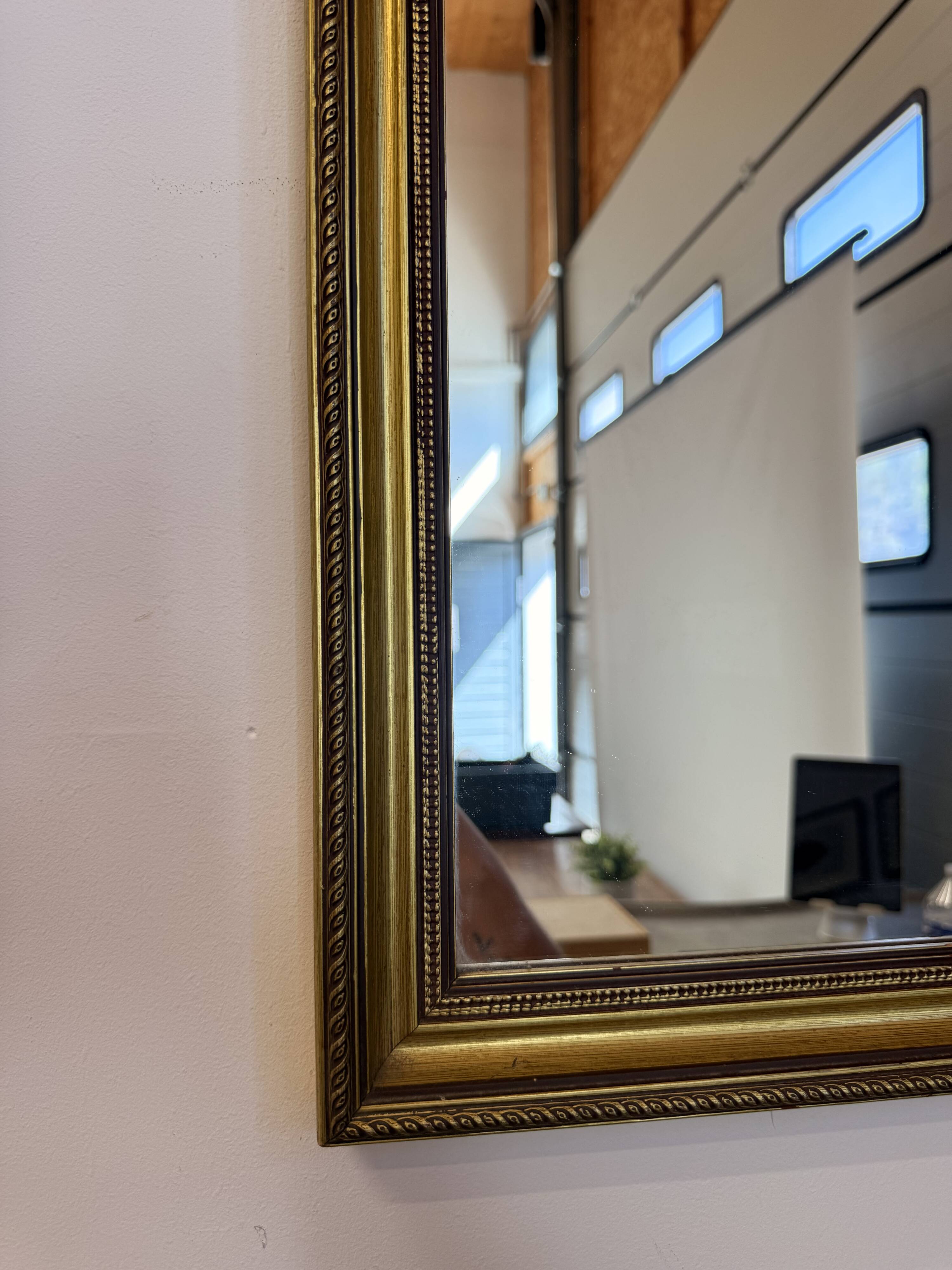 Vintage rectangular wall mirror with a golden wooden frame.