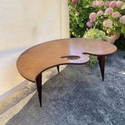 Mid-century coffee table with a palette shape and splayed legs.