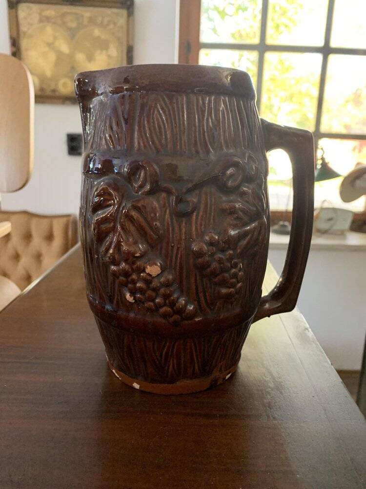 Hungarian folk ceramic pitcher with a brown glossy finish and relief decoration of vine.