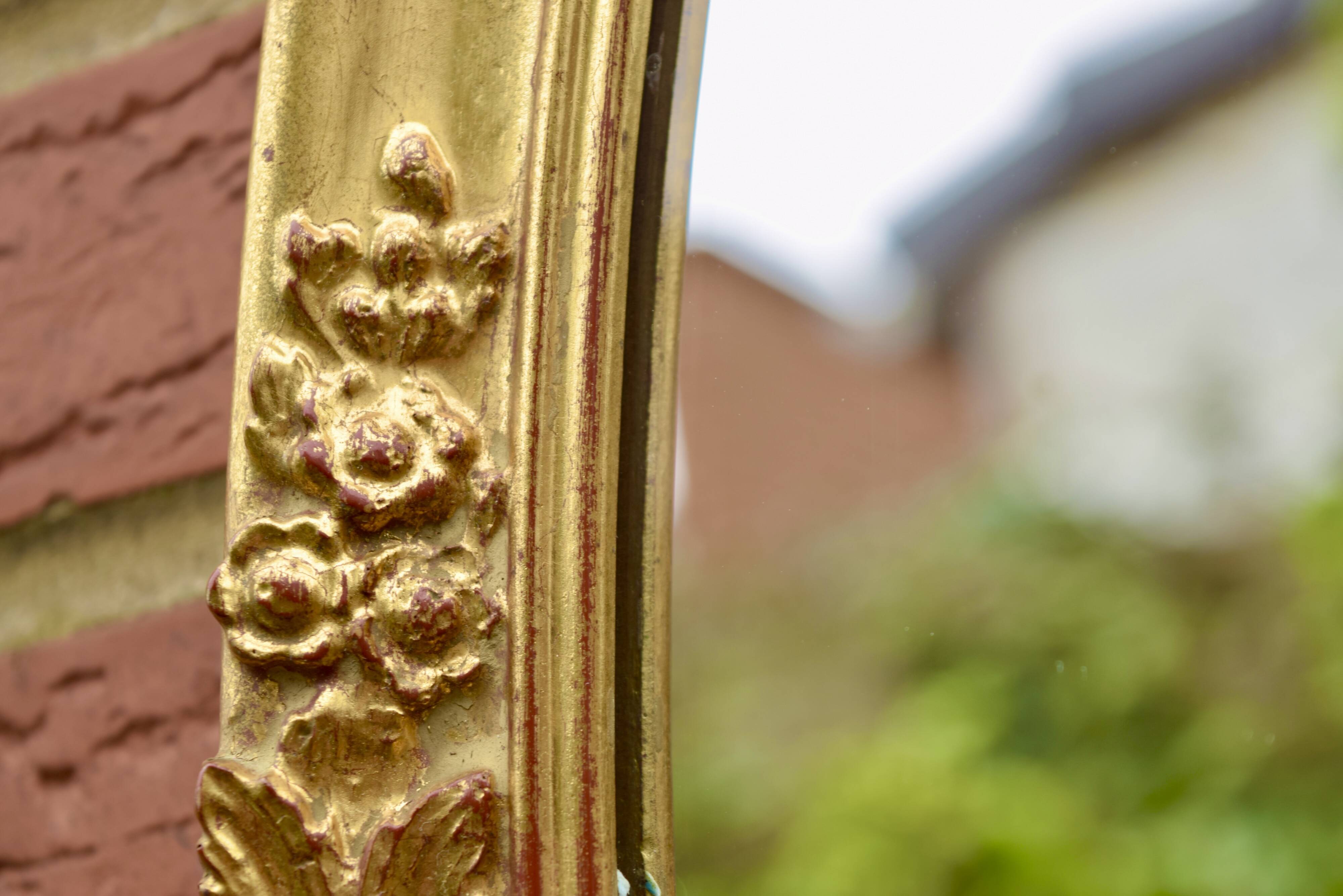 Old large oval wall mirror in golden resin