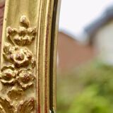 Old large oval wall mirror in golden resin