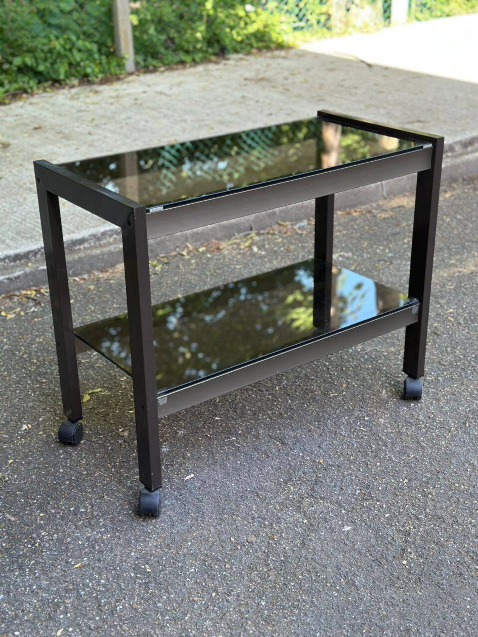 Vintage 1970s rolling bar cart made of metal and smoked glass.