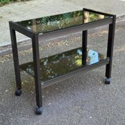 Vintage 1970s rolling bar cart made of metal and smoked glass.