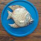 Vallauris ceramic wall sculpture of a relief fish on a blue plaque.