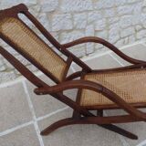 Antique folding chair with caned seat and backrest made of wood.