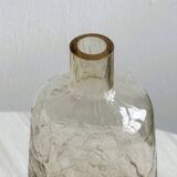 Translucent pinkish iridescent cracked glass bottle.