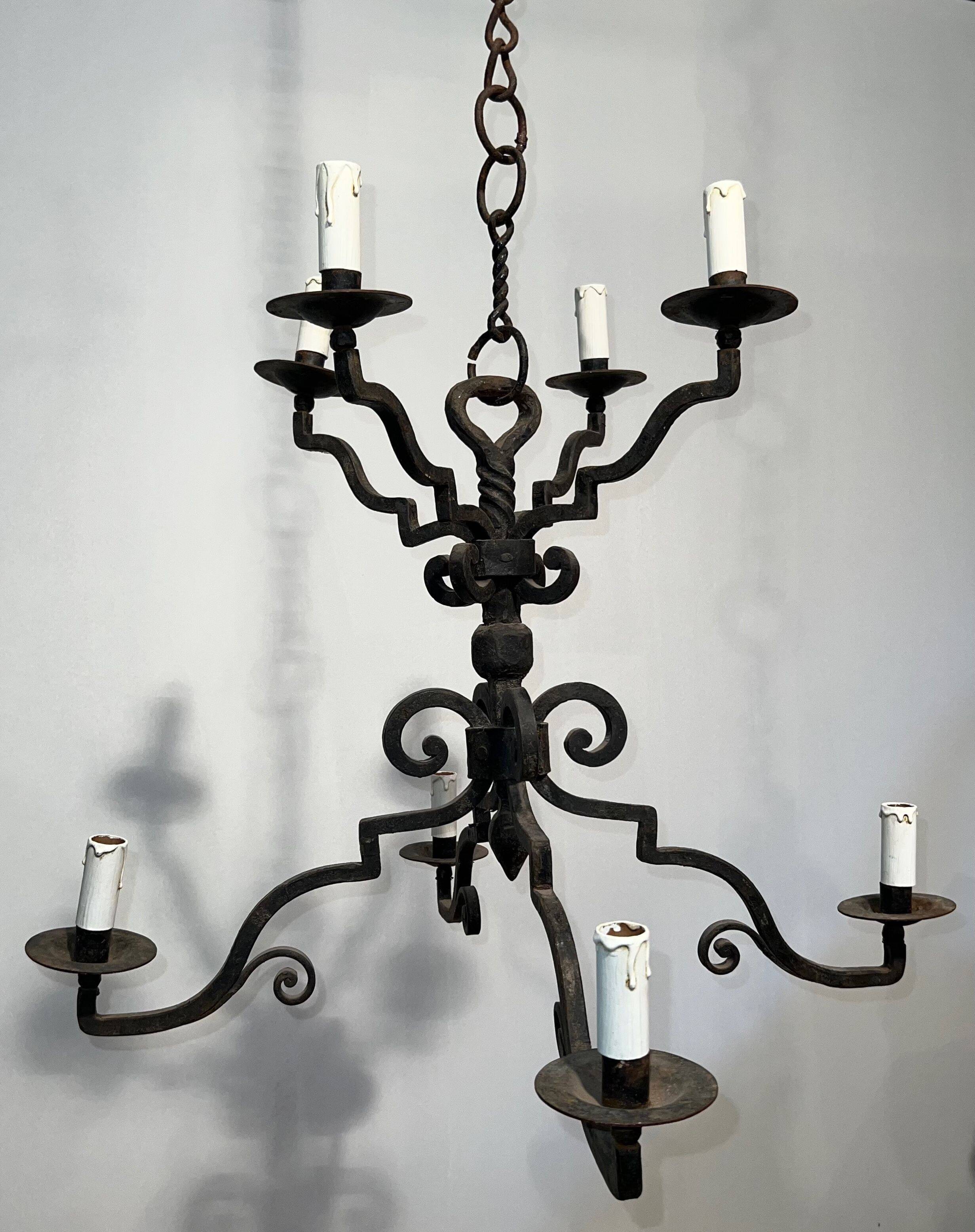 Two-tiered wrought iron chandelier with eight light arms in Gothic style.