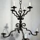 Two-tiered wrought iron chandelier with eight light arms in Gothic style.