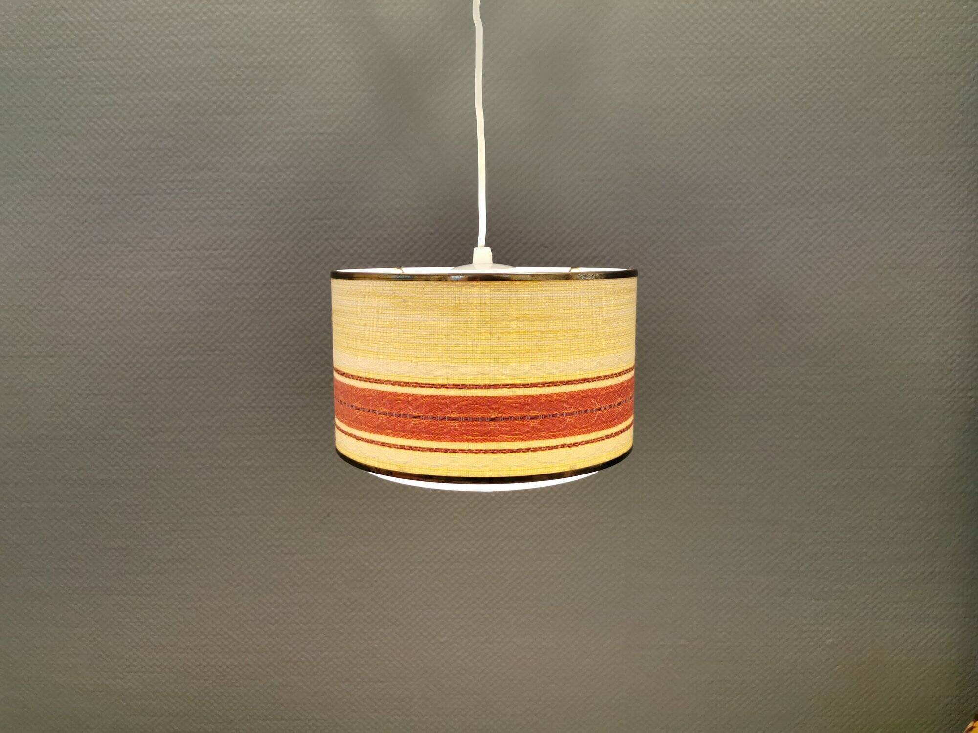 Hanging lamp with brass-coloured details, made of fabric with intact plastic bottom grille.